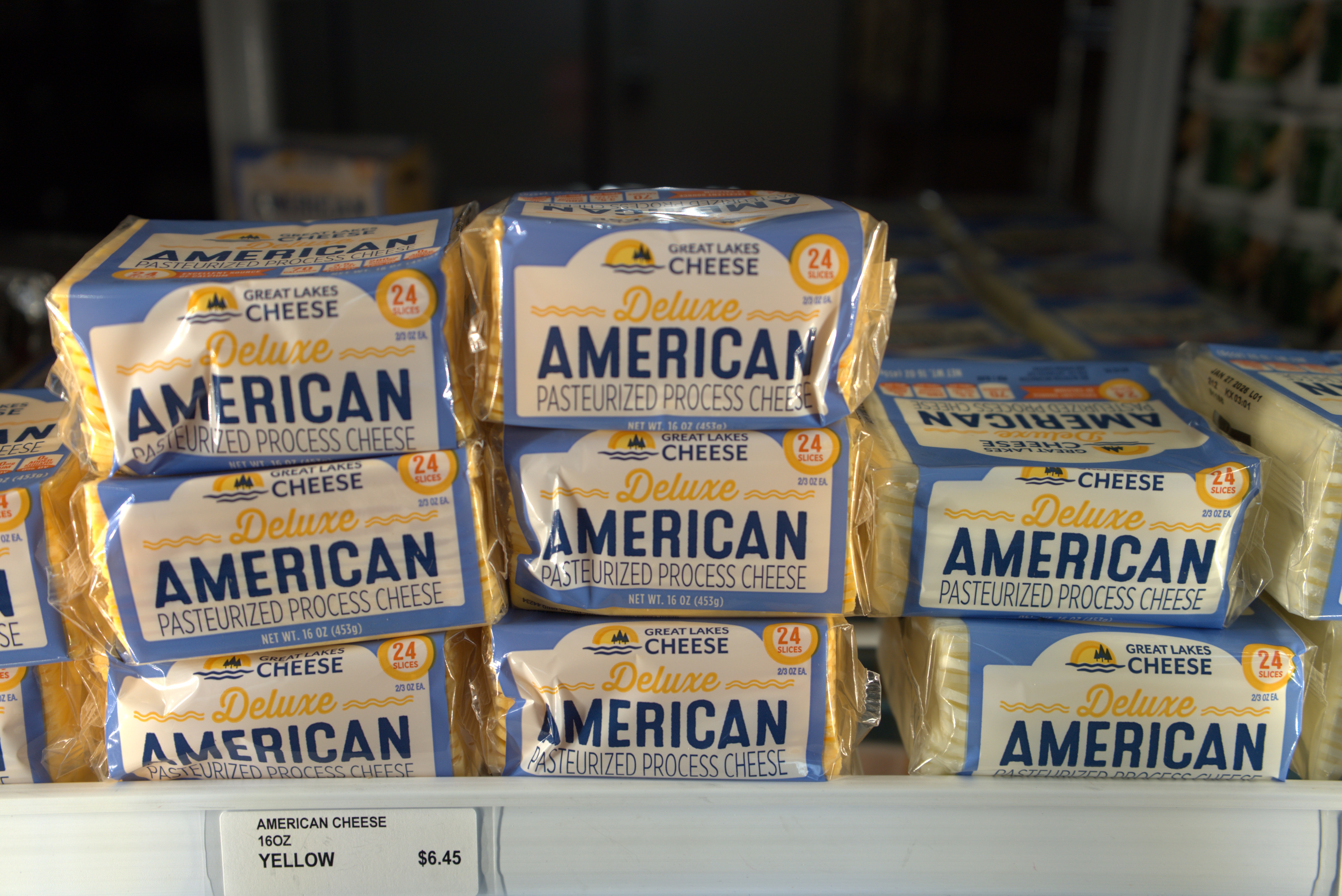 Variety of food products on a supermarket shelf, including milk, cereal, and pasta with colorful packaging.