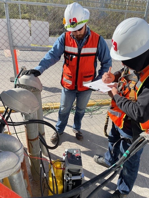 A MacBook with lines of code on its screen on a busy desk