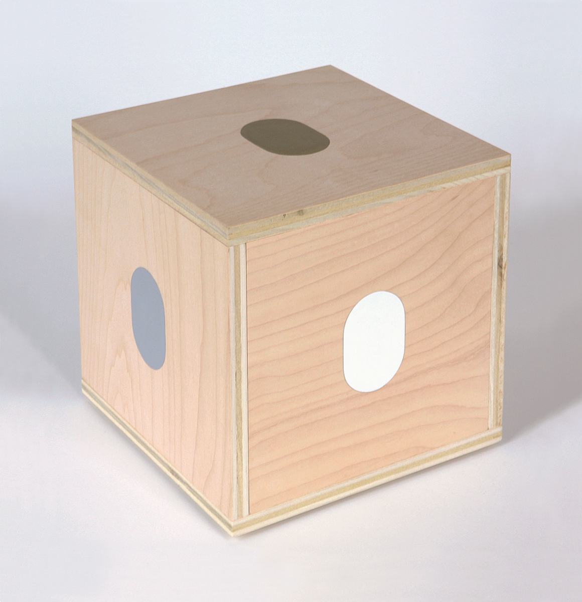 A plywood cube with gold, grey and white ovals painted on the top and sides.