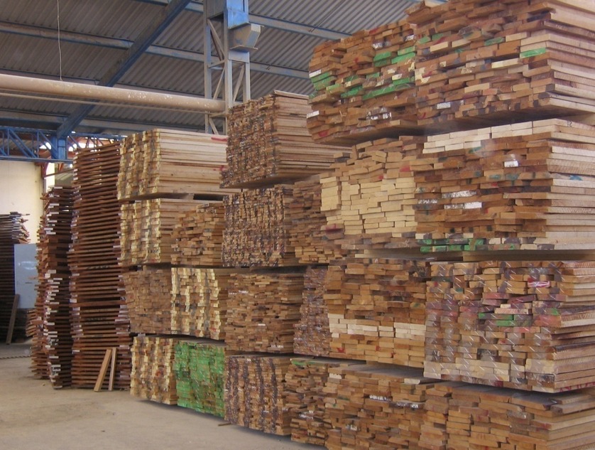 Pilas de tablas de madera almacenadas en un aserradero o almacén industrial
