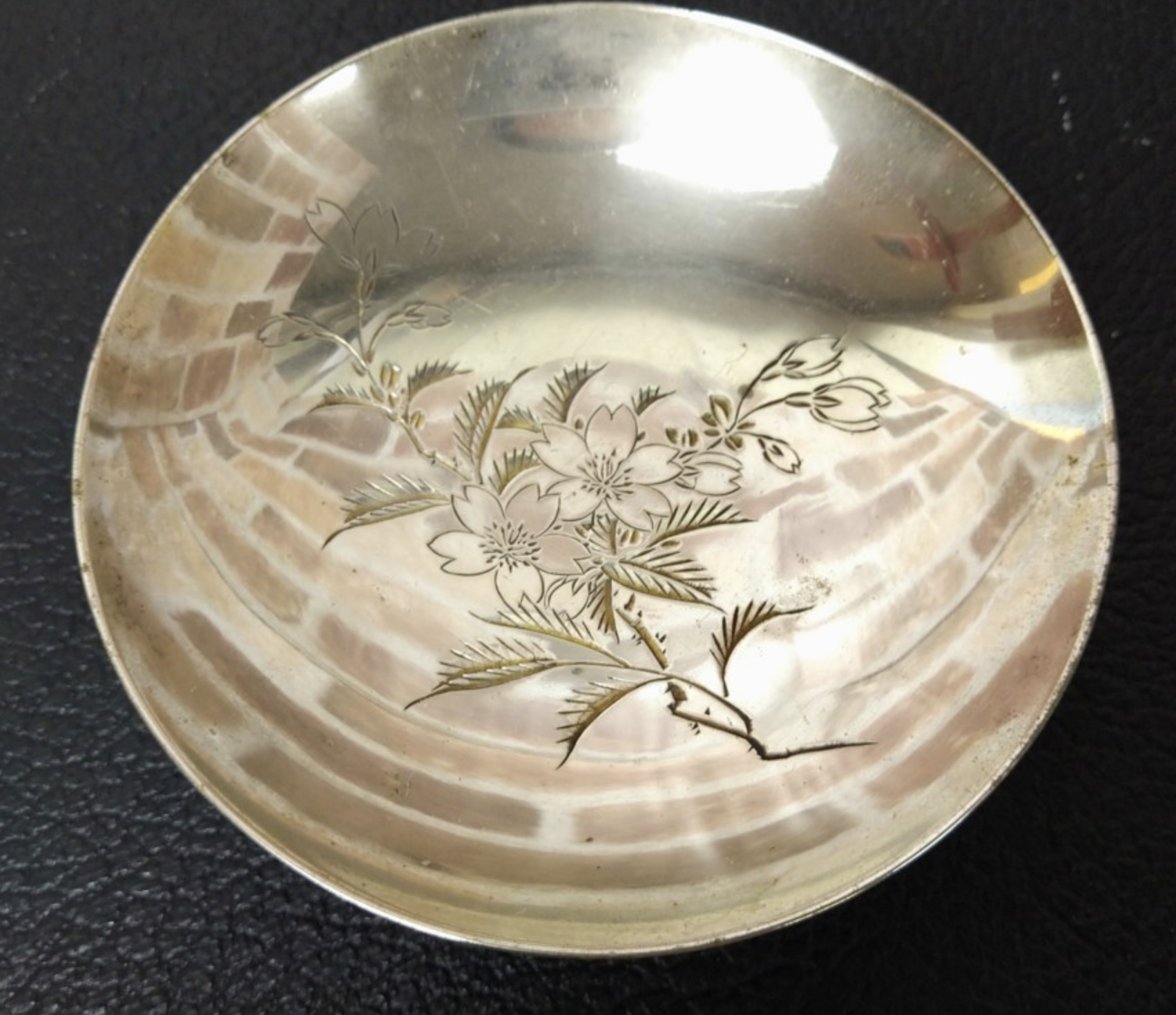 Close up view of cup - an historic sterling silver sake cup that was once presented to the 3rd Company, Instruction Battalion of the Toyama Military Academy pre-1945.  Around the outer rim is engraved 陸軍戸山学校教導大隊第三中隊記念