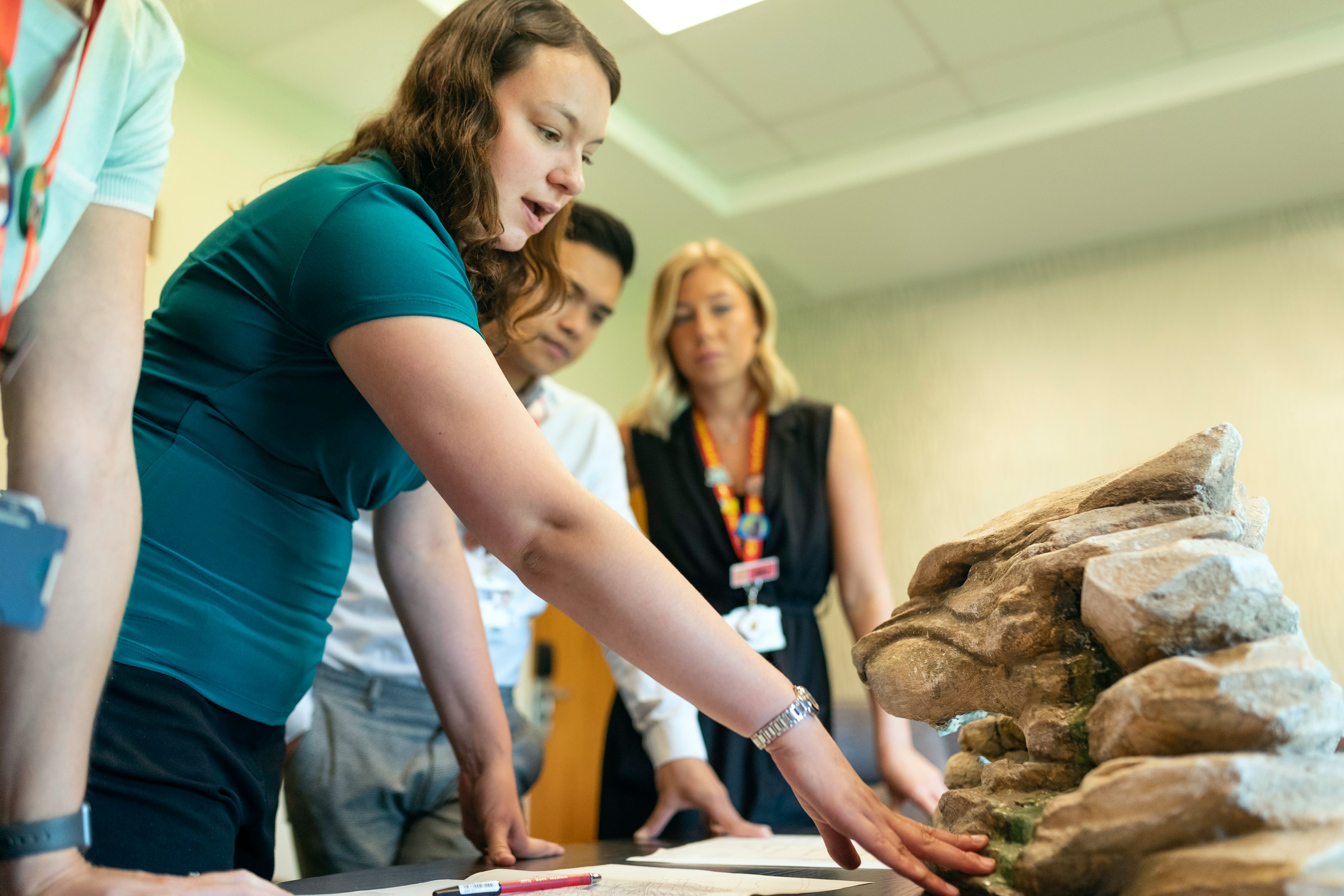 mujer con camiseta azul de pie junto a mesa de madera marrón