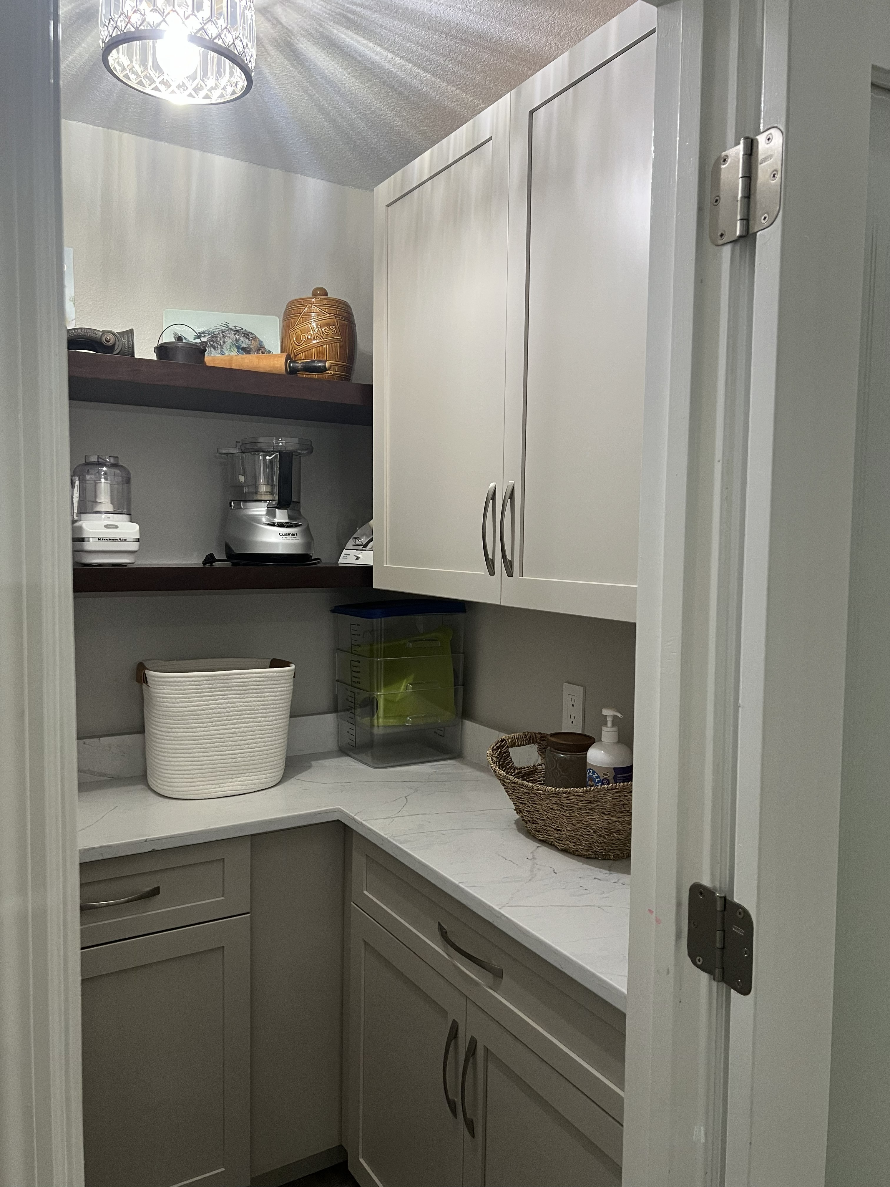 Perfectly paired stained floating shelves with painted cabinetry for a lovely pantry storage area.