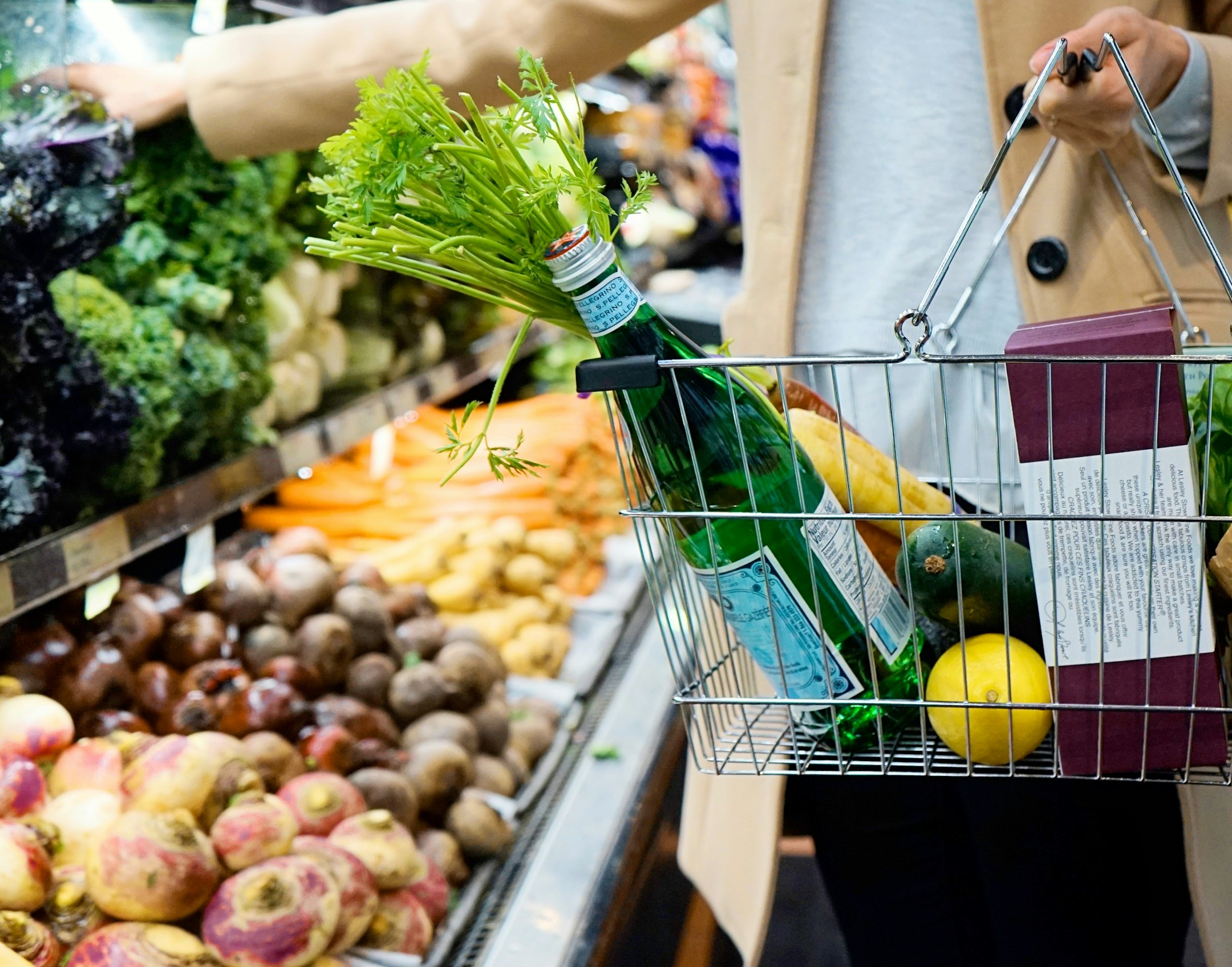Pasillo de supermercado con estantes repletos de frutas y verduras frescas, como tomates, brócoli y naranjas.