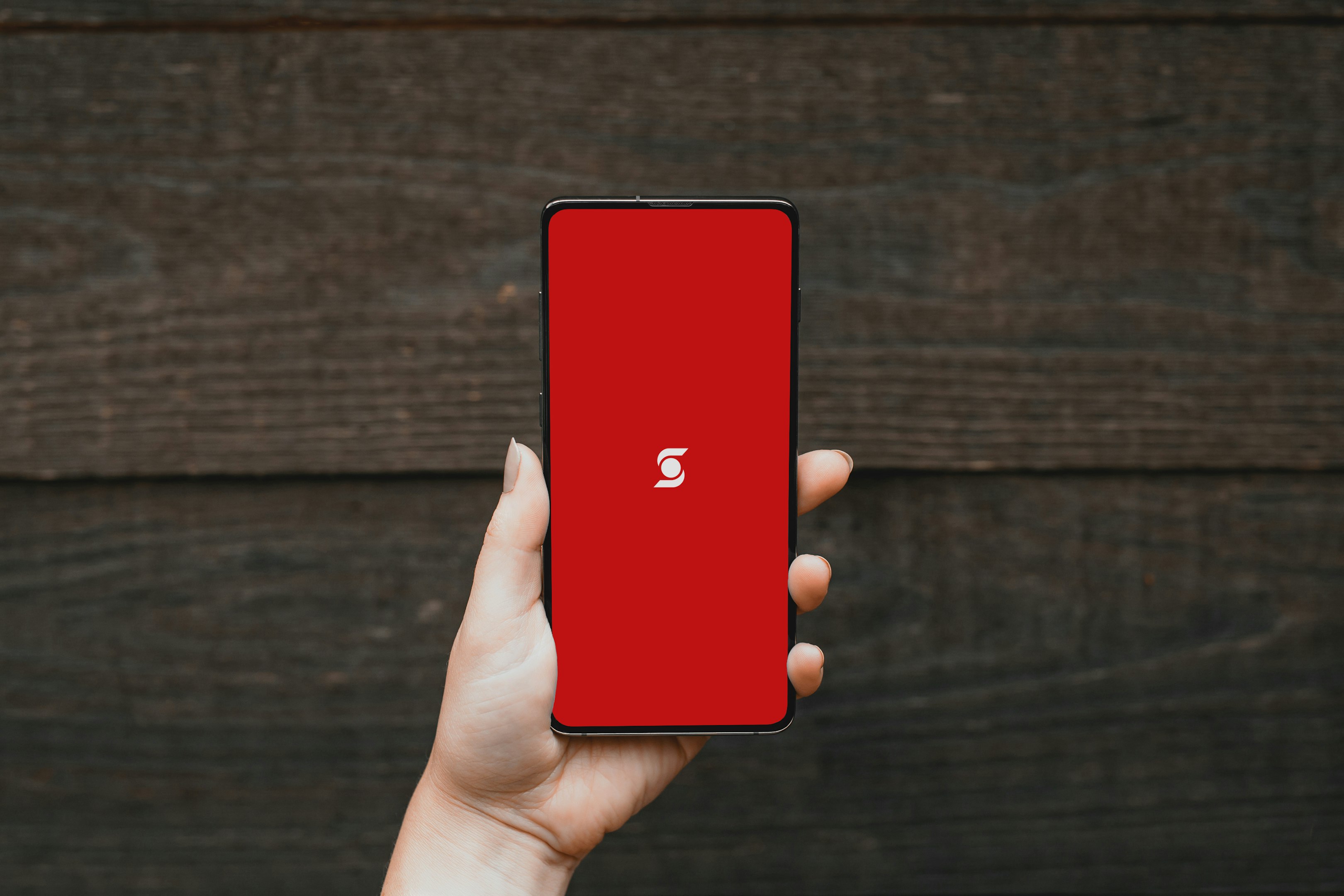 una persona sosteniendo un teléfono celular rojo en su mano