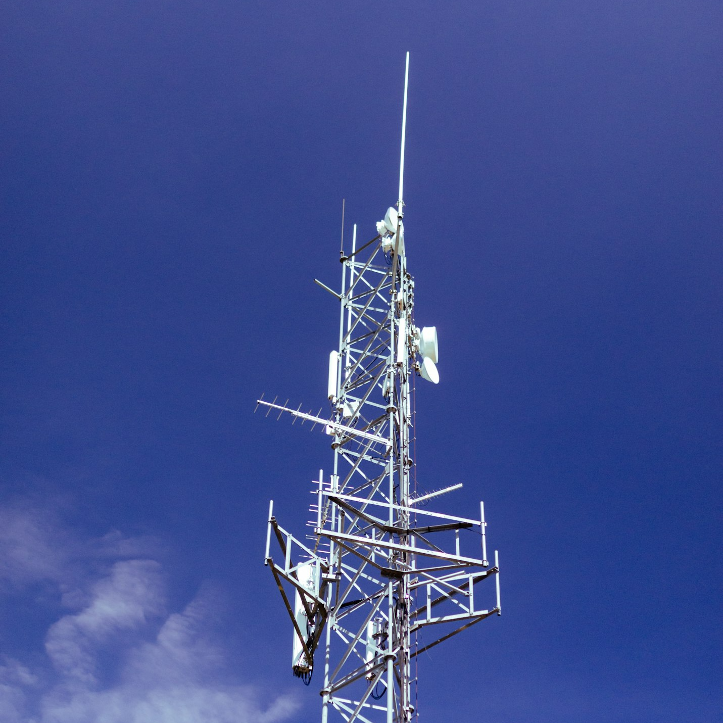 Mujer en traje profesional usando laptop en oficina moderna con pantalla grande mostrando mapa del mundo y datos.