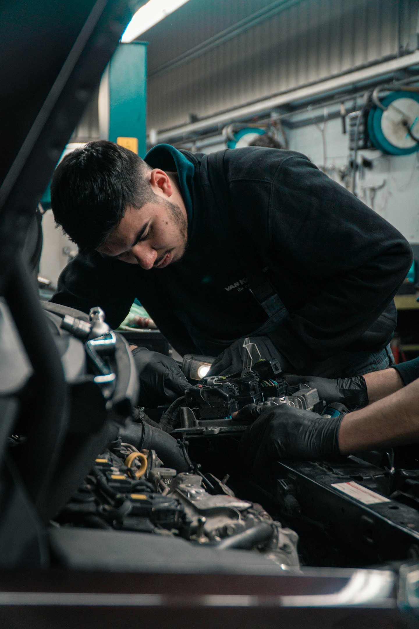 Mechanic working on a car engine in a garage setting.