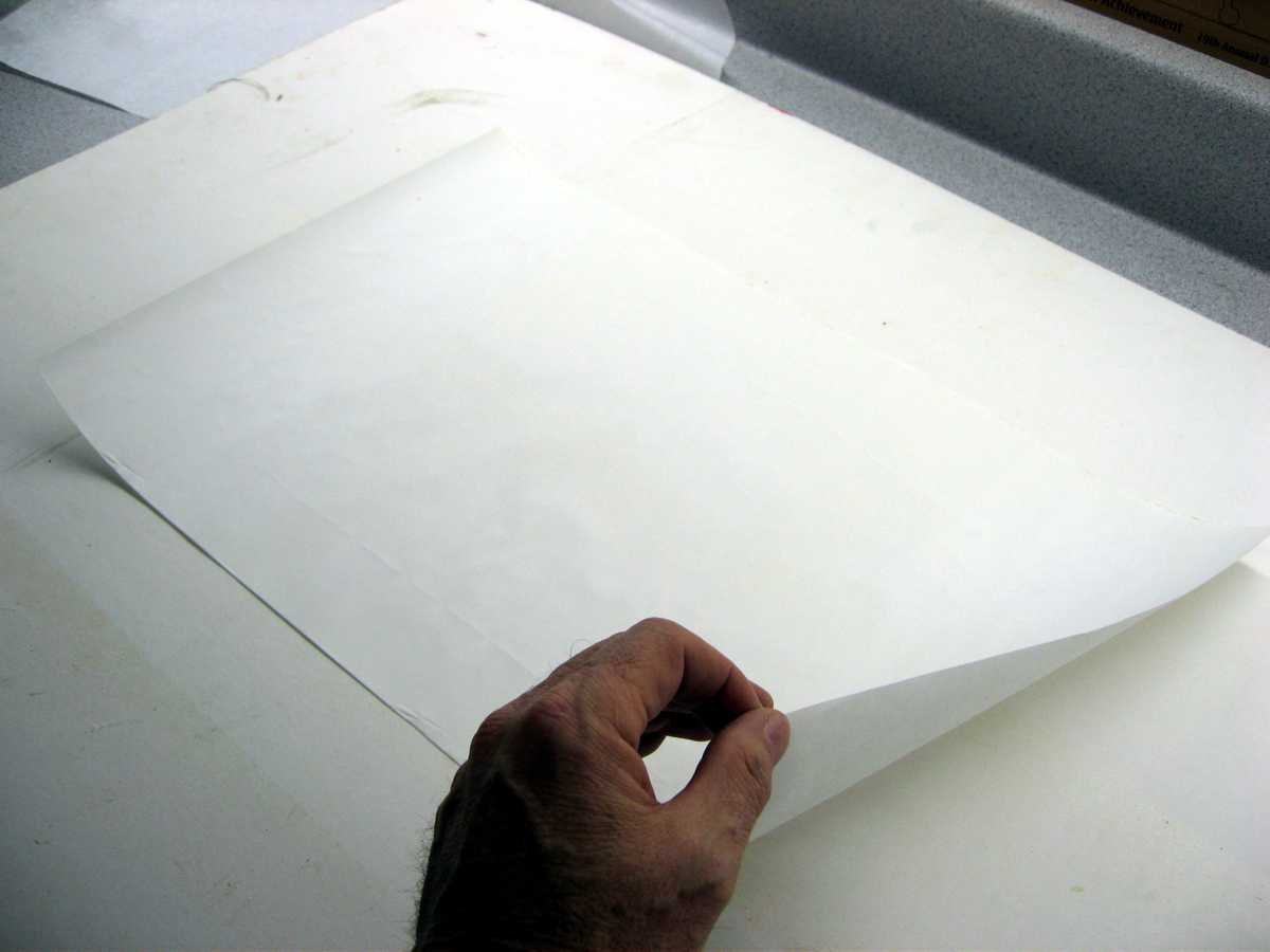 After applying the spray adhesive, stick the backing sheet to a piece of cardboard. Peel off the backing sheet. Repeat that process for 3 or 4 times. This will reduce the tack of the adhesive.