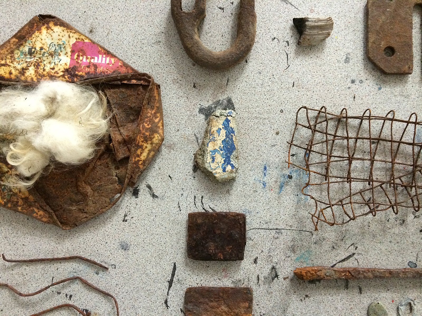 A closeup of rusted and other found objects placed on a grey speckled surface.