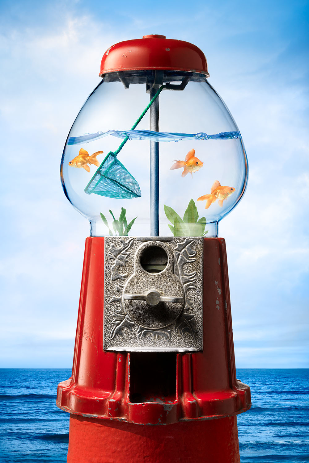 Humorous photomontage of vintage gumball machine with glass bowl filled with goldfish swimming in water.  