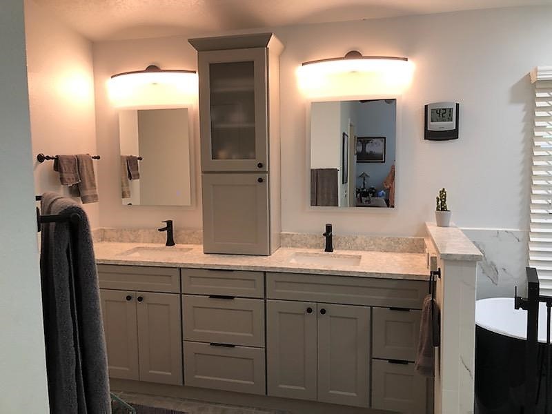 Dual vanities with tall utility cabinet in the middle for extra storage.  The Cambria Quartz countertop and backsplash compliment the bright clean space.