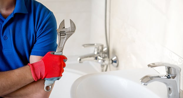 Plumber with Wrench Standing in Bathroom