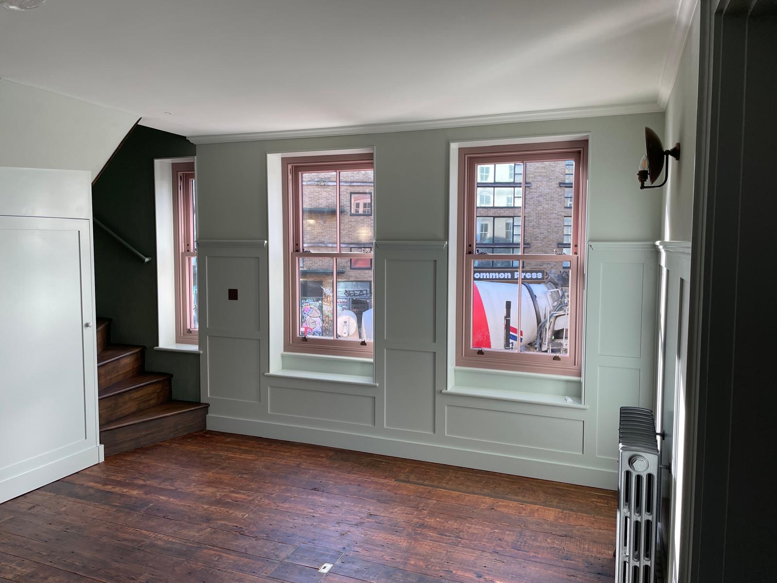 man in black t-shirt and gray pants standing near white wall