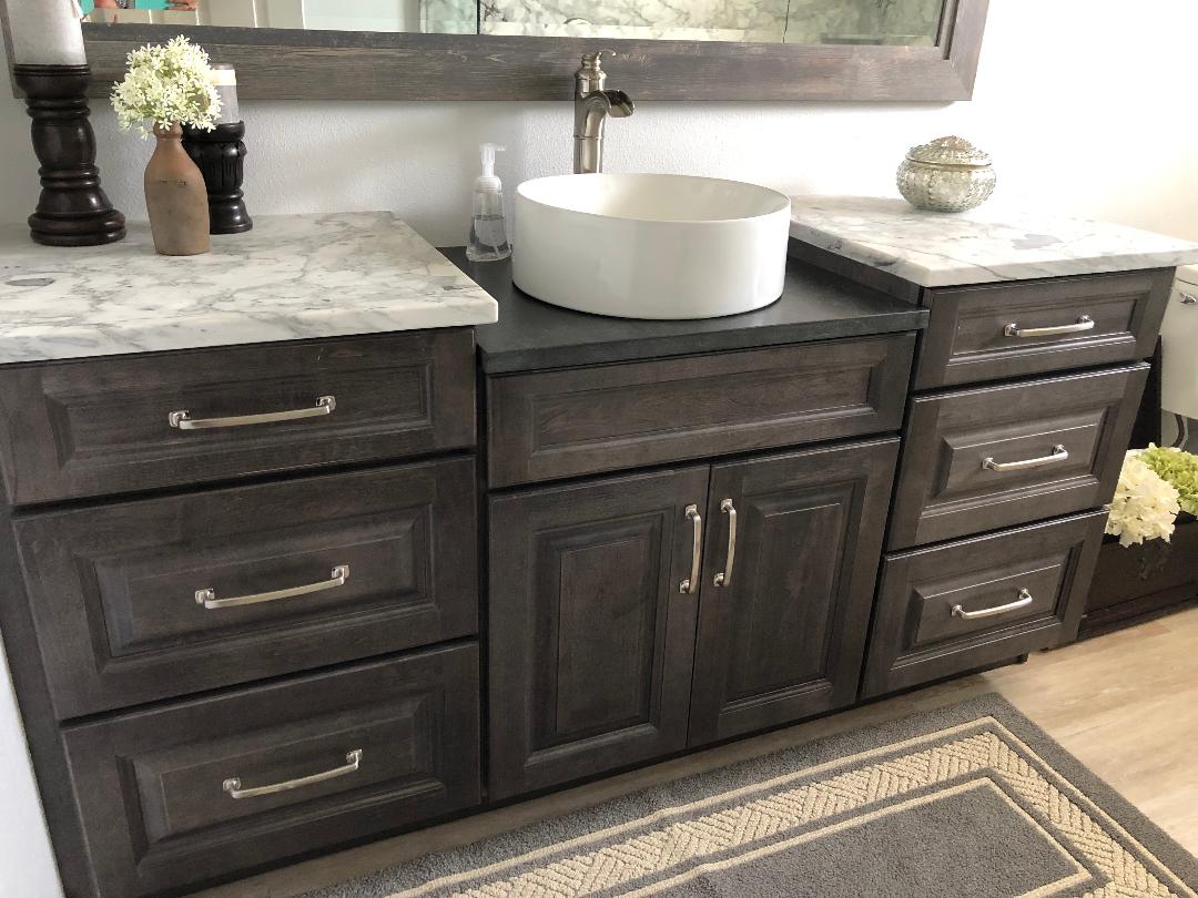 Featuring an elegant vanity with a single white vessel sink with satin nickel hardware.