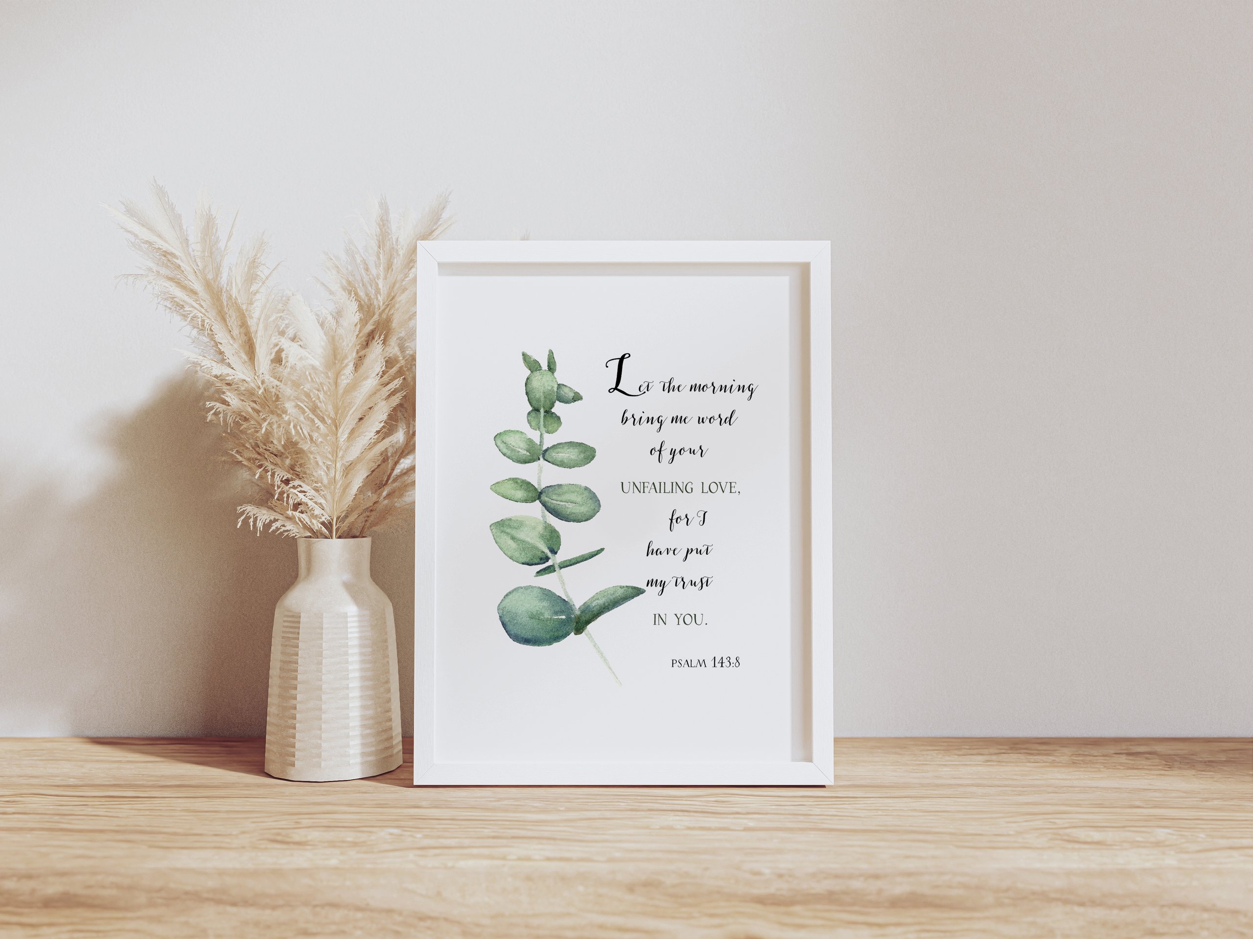 Decorative framed quote with eucalyptus print and pampas grass in vase on a wooden surface.