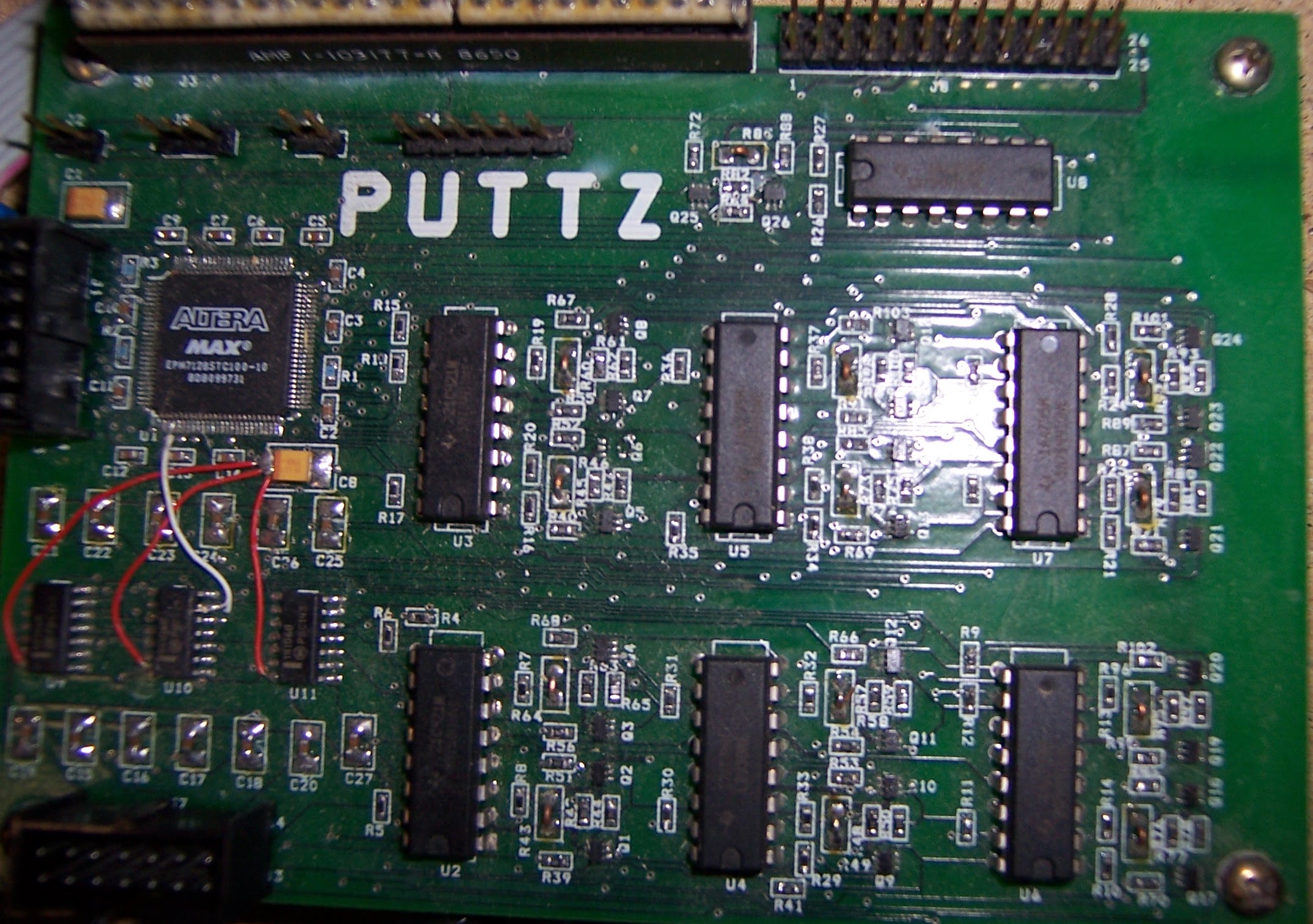 Close-up view of a green circuit board with multiple black integrated circuits and an Altera MAX chip labeled 'PUTTZ'.