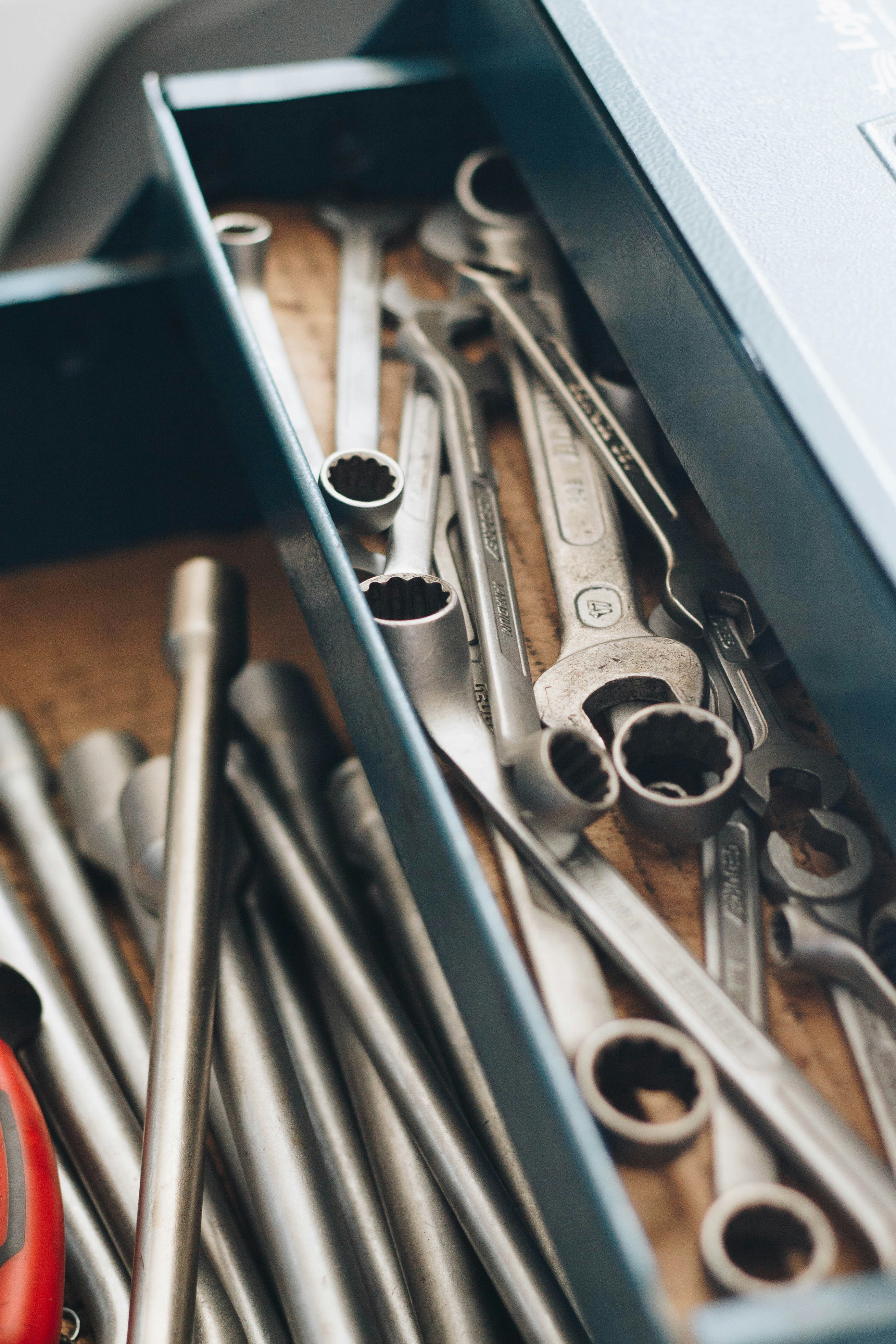 Open toolbox drawer with assorted metal wrenches and socket tools.
